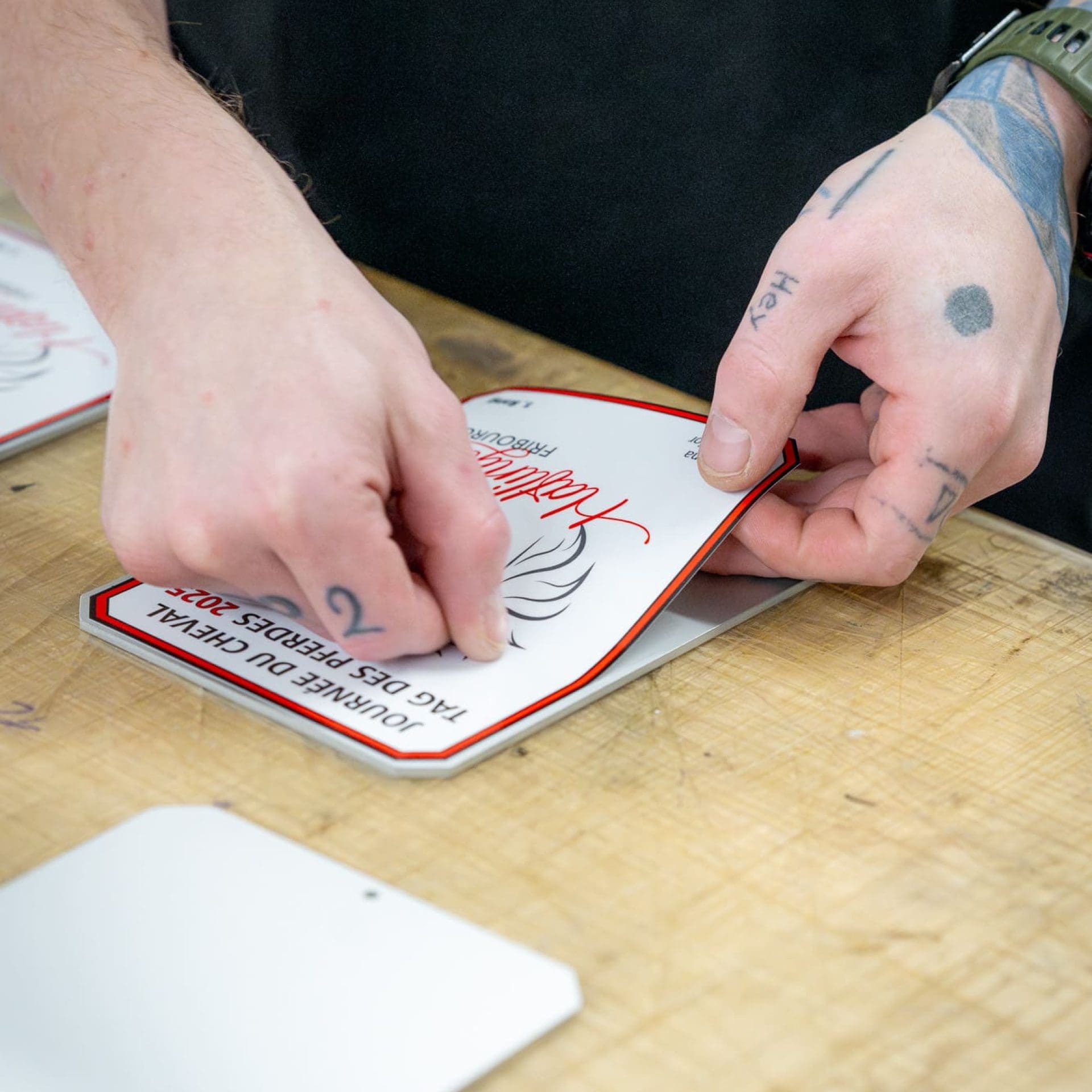 Sorgfältige Handarbeit trifft auf moderne Technik Mitarbeiter des Entlebucher Medienhauses bei der Produktion individueller Stallplaketten – sorgfältige Gestaltung und hochwertige Verarbeitung in der hauseigenen Druckerei